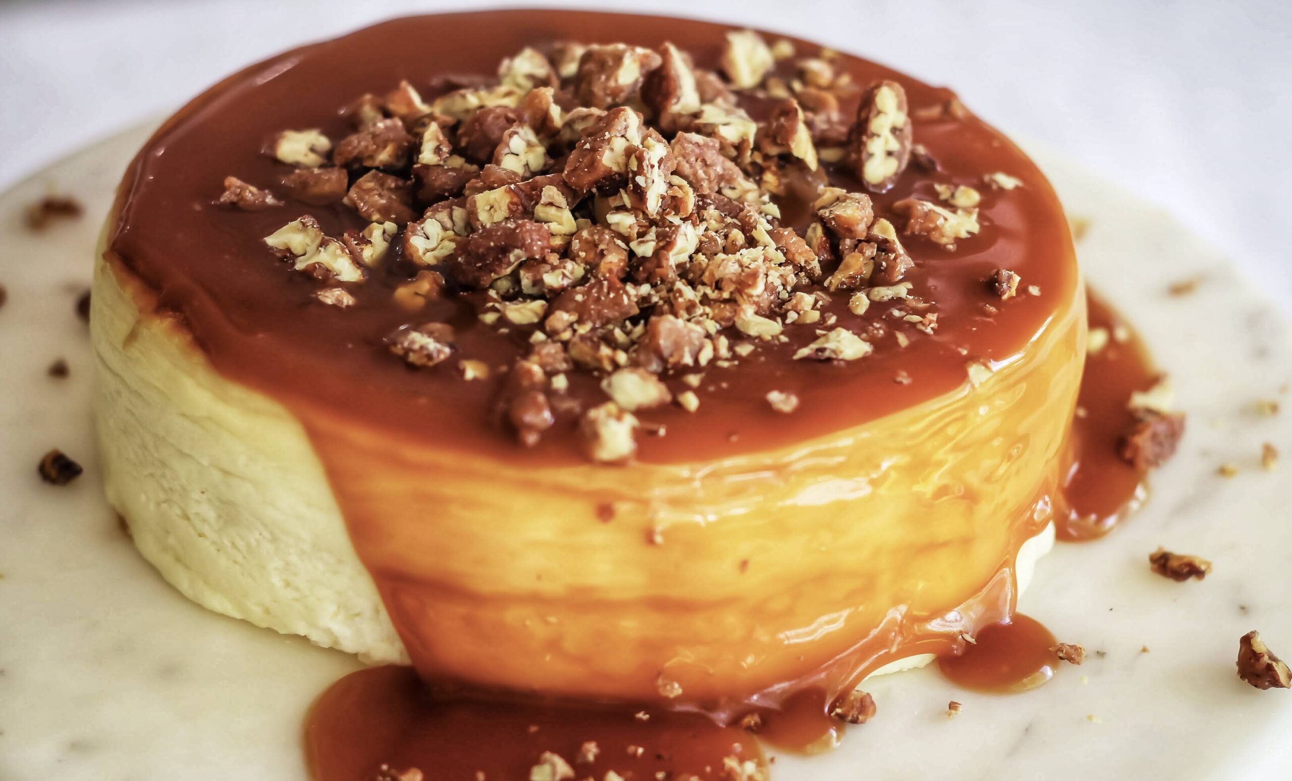A cheesecake with nuts and caramel sauce on top.