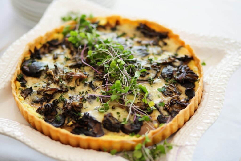 A quiche with mushrooms and cheese on top.