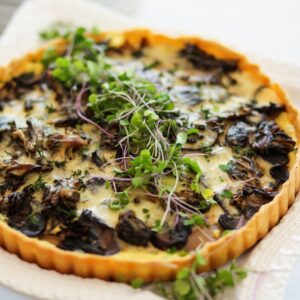 A quiche with mushrooms and cheese on top.