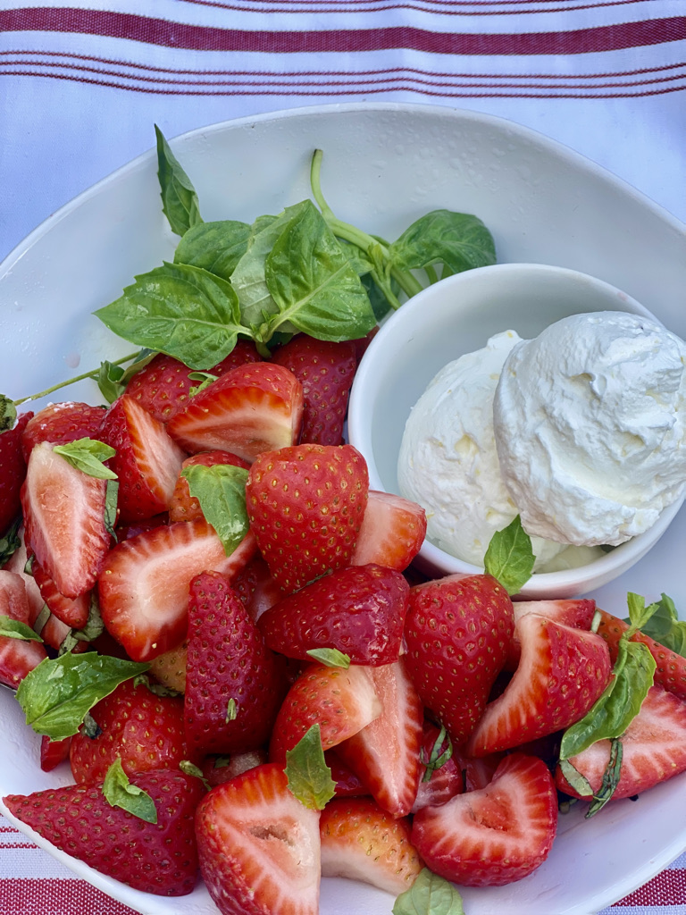 A plate of strawberries and whipped cream on the side.
