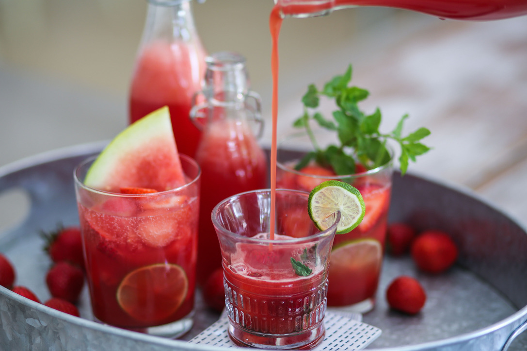 A tray with several glasses of watermelon juice.