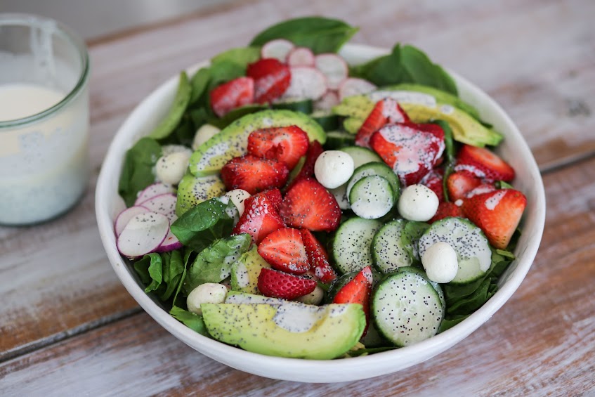 A bowl of salad with cucumbers, strawberries and radishes.