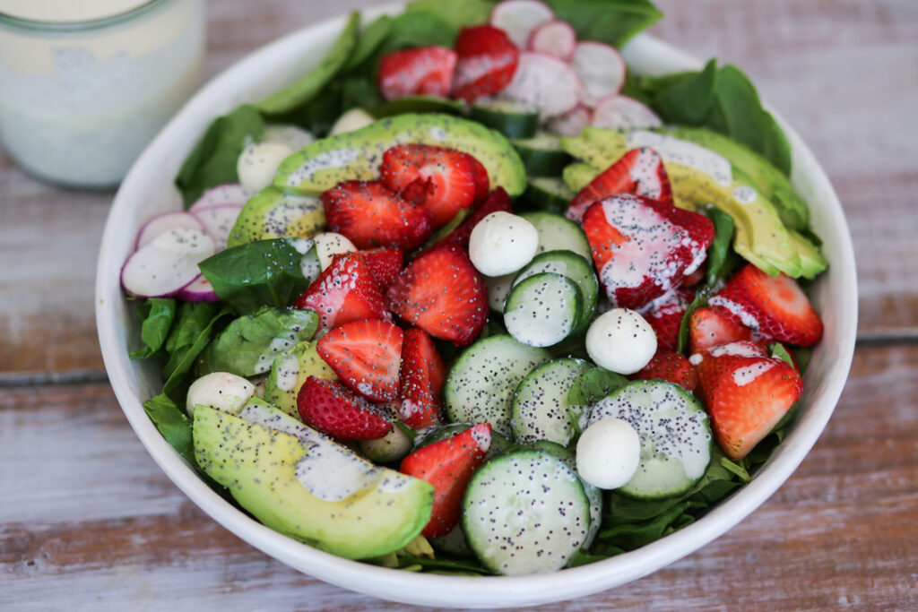 A bowl of salad with strawberries, cucumbers and avocado.