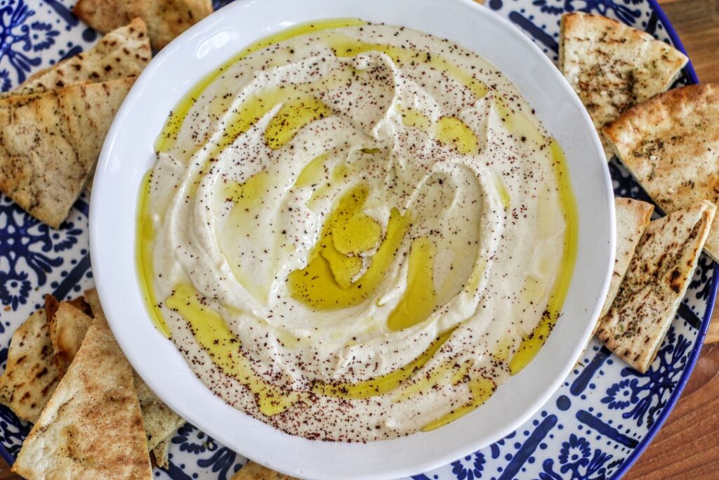 A bowl of hummus with olive oil and spices.