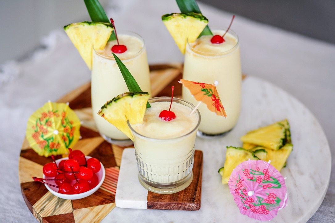 Three glasses of pina colada with pineapple garnishes.