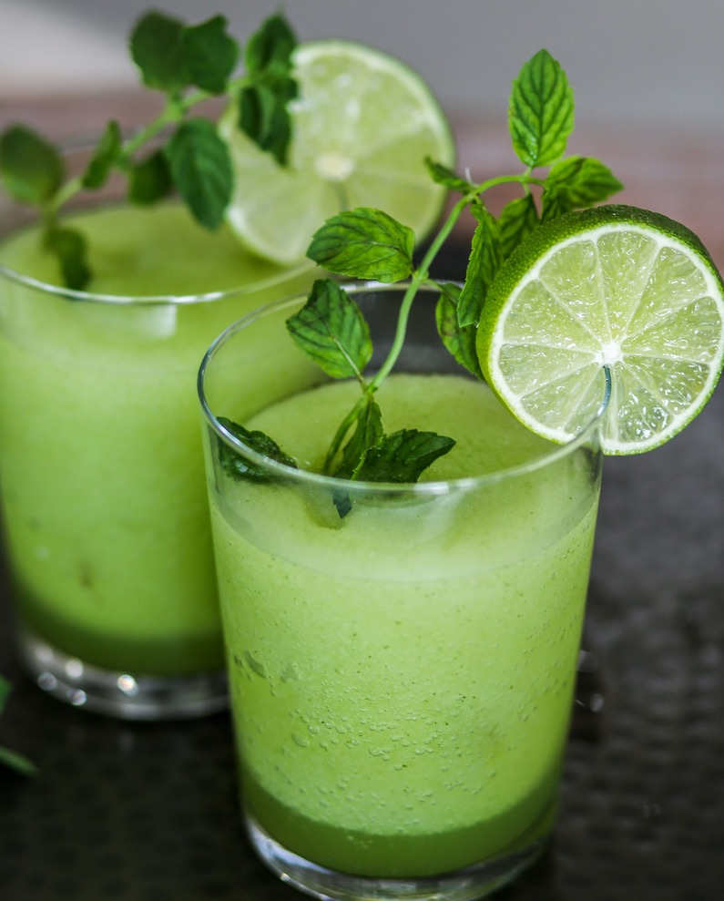 Two glasses of green drink with lime and mint.