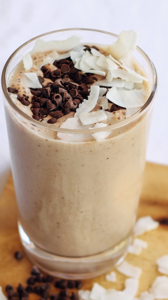 A glass of chocolate shake with coconut and nuts.