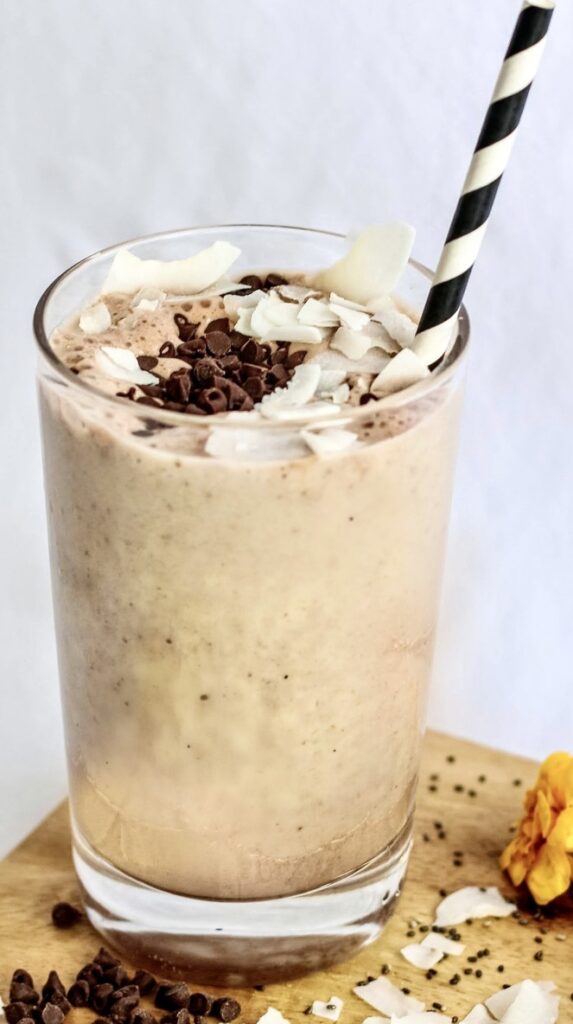 A glass of milk with cookies and chocolate on top.