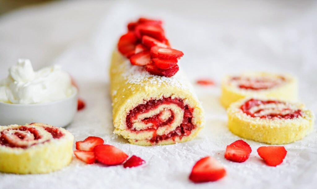 A roll cake with strawberries on top of it.
