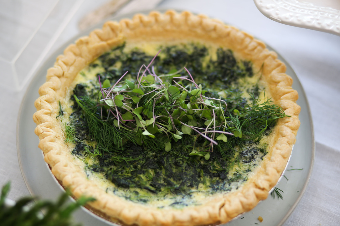 A quiche with greens in it sitting on top of a table.