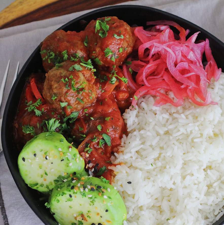 A bowl of rice, meatballs and vegetables.