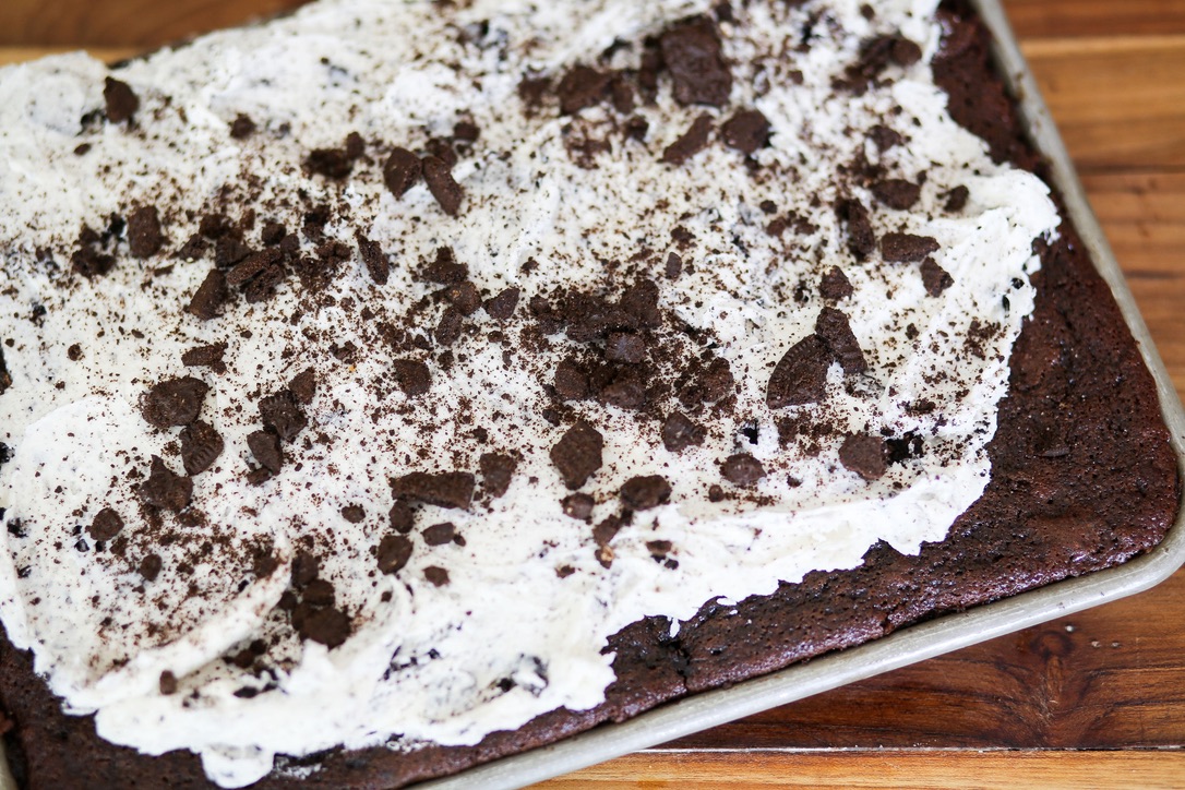 A chocolate cake with white frosting and cookies.