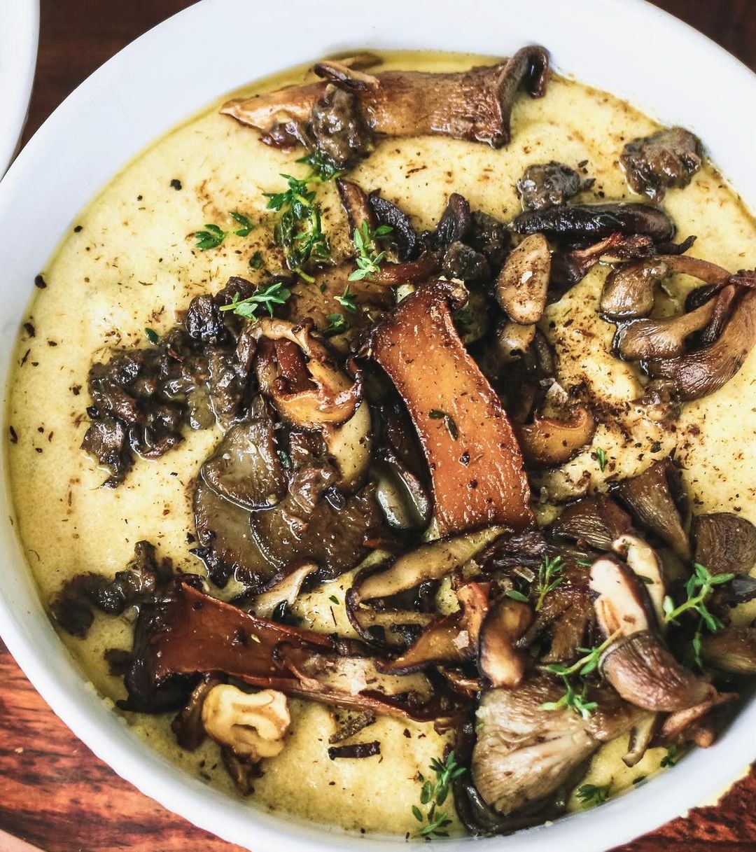 A bowl of food with mushrooms and herbs.