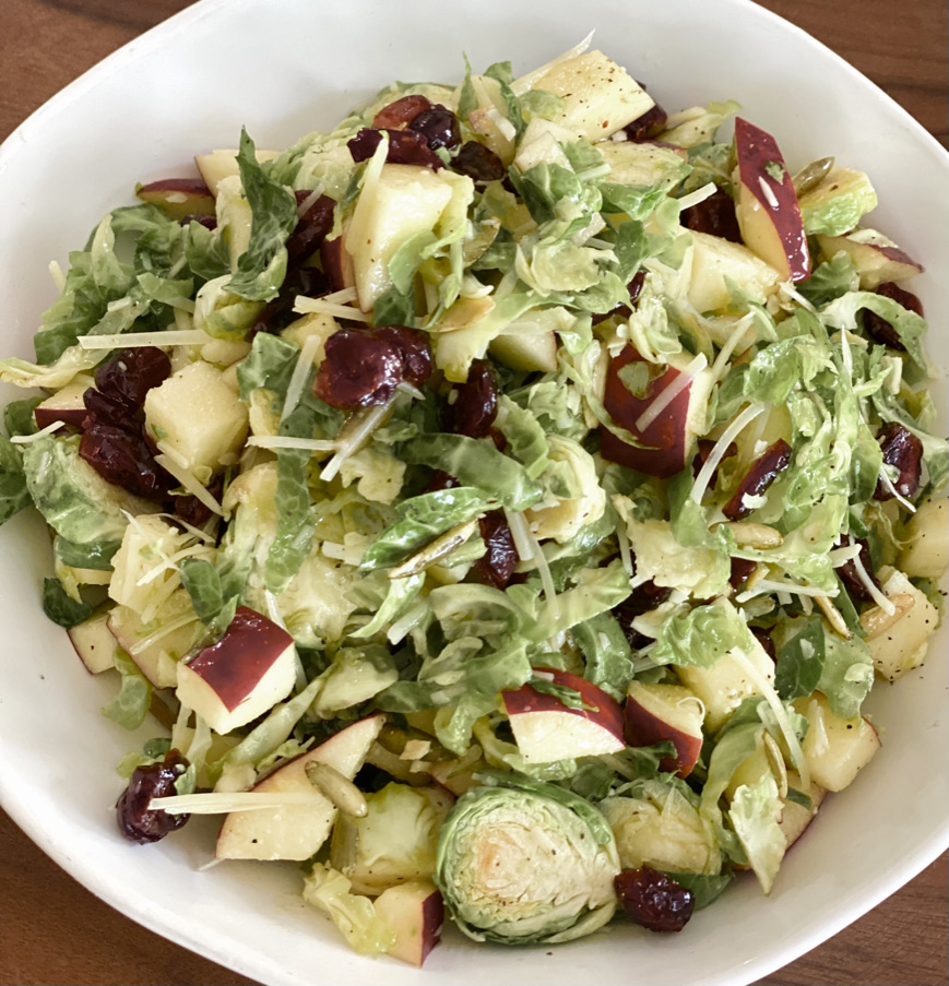 A bowl of salad with apples, cabbage and cranberries.