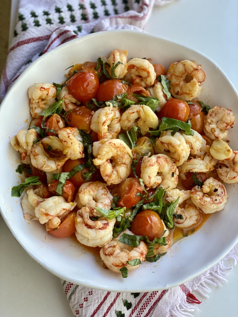 A white bowl filled with shrimp and tomatoes.