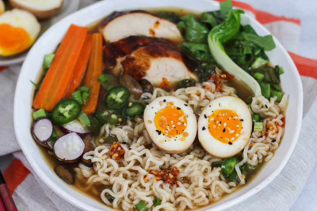 A bowl of ramen with vegetables and an egg.