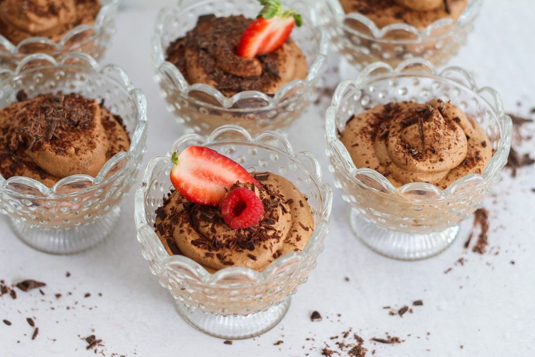 A group of desserts in glass dishes with strawberries.