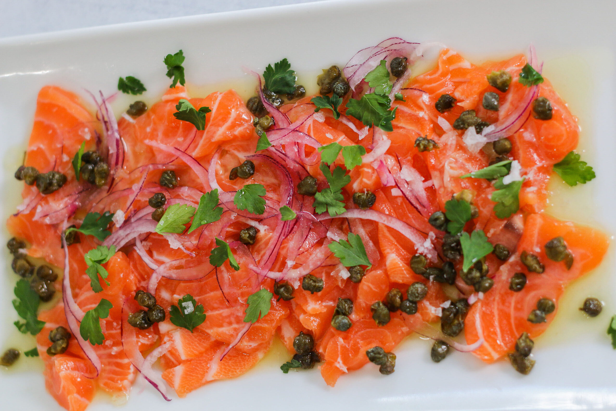 A plate of food with salmon and capers.