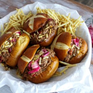 A bowl of hot dogs and fries on the table.