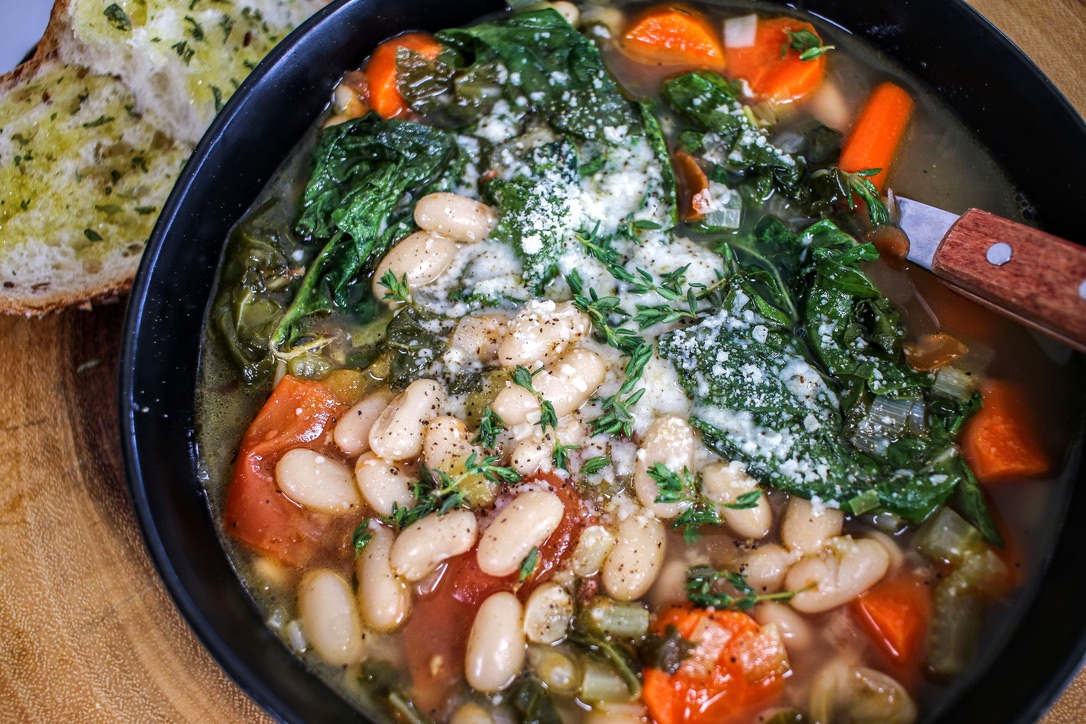 A bowl of beans and vegetables with spinach.