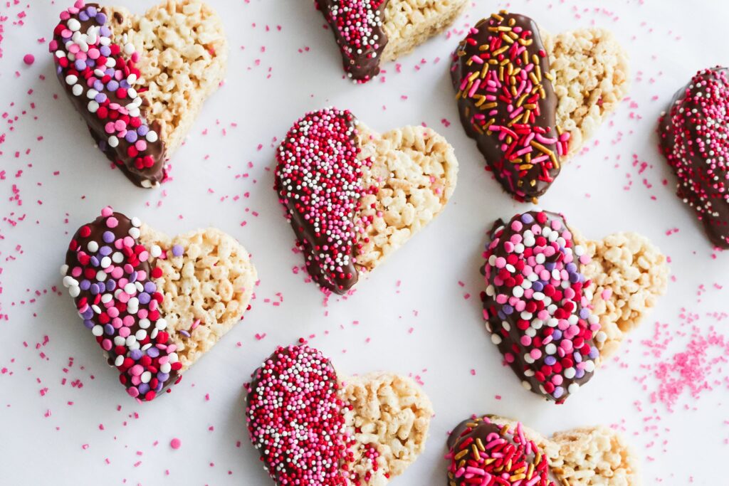A white table topped with heart shaped rice krispie treats.