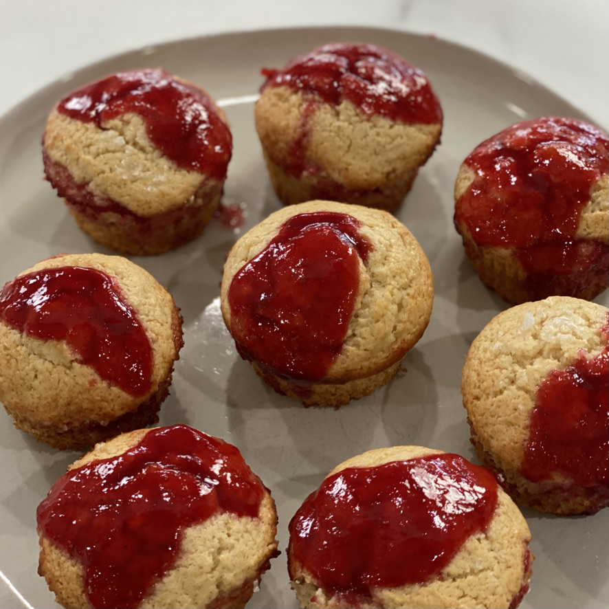 A plate of muffins with strawberry jam on top.