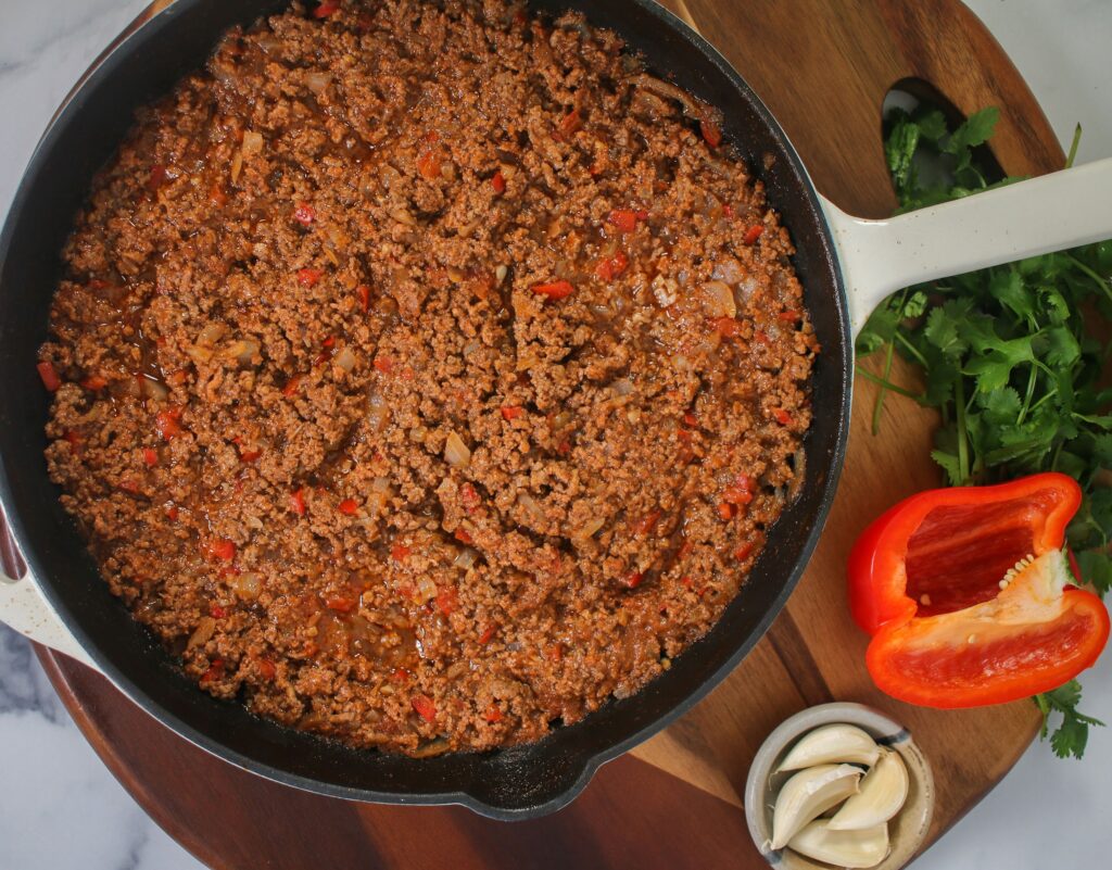 A pan of ground meat with vegetables on the side.