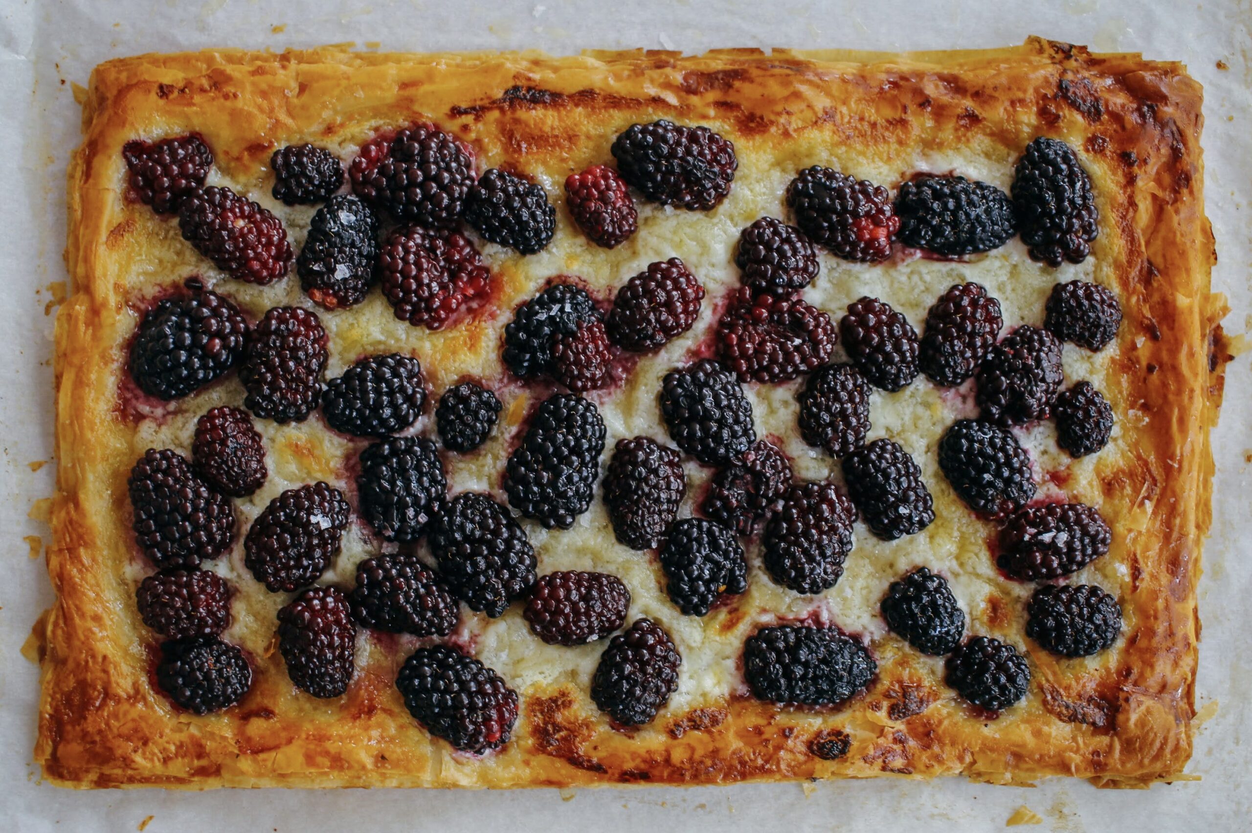 A pizza with blackberries on top of it.