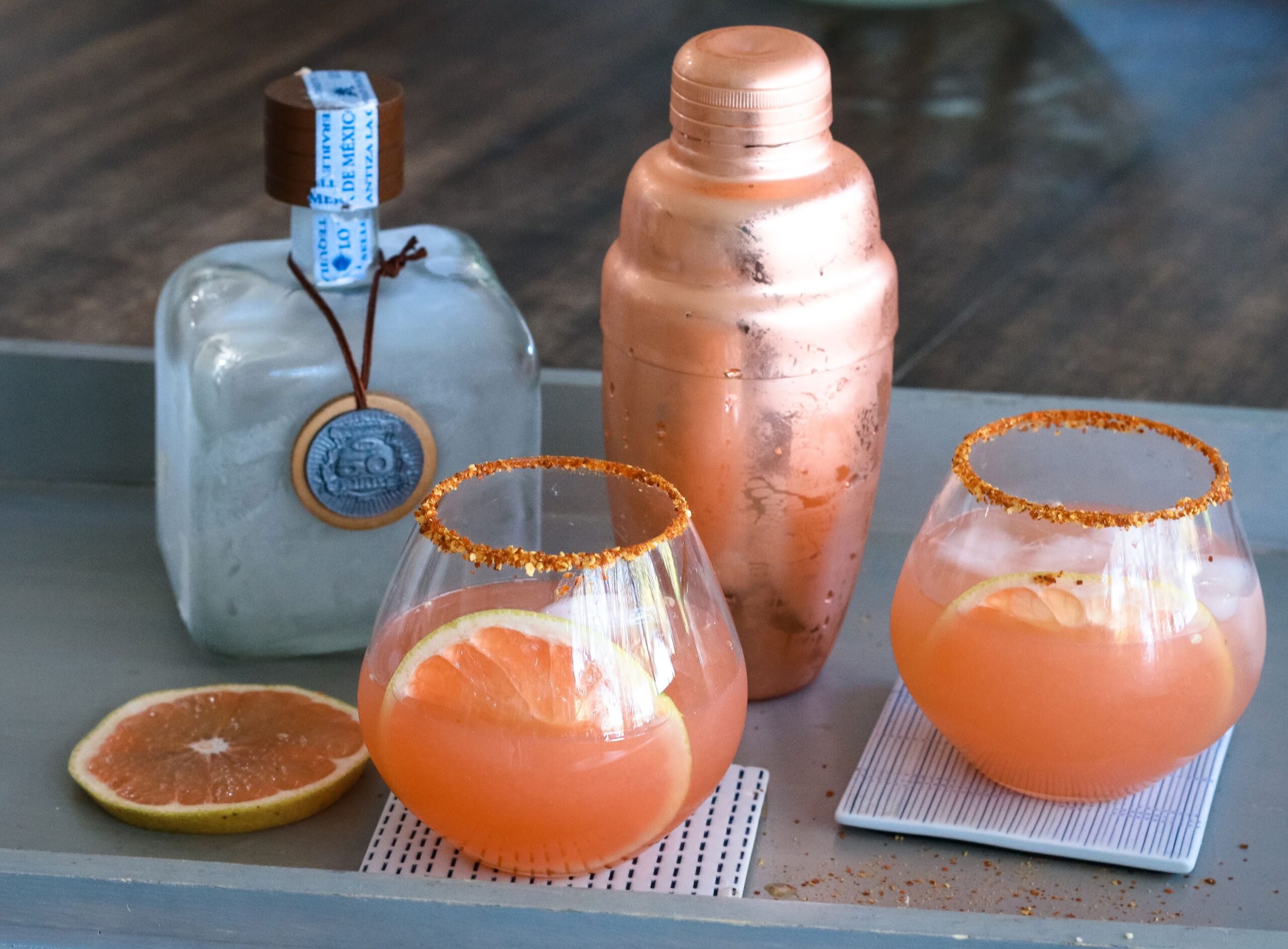A table with two glasses and a cocktail shaker.