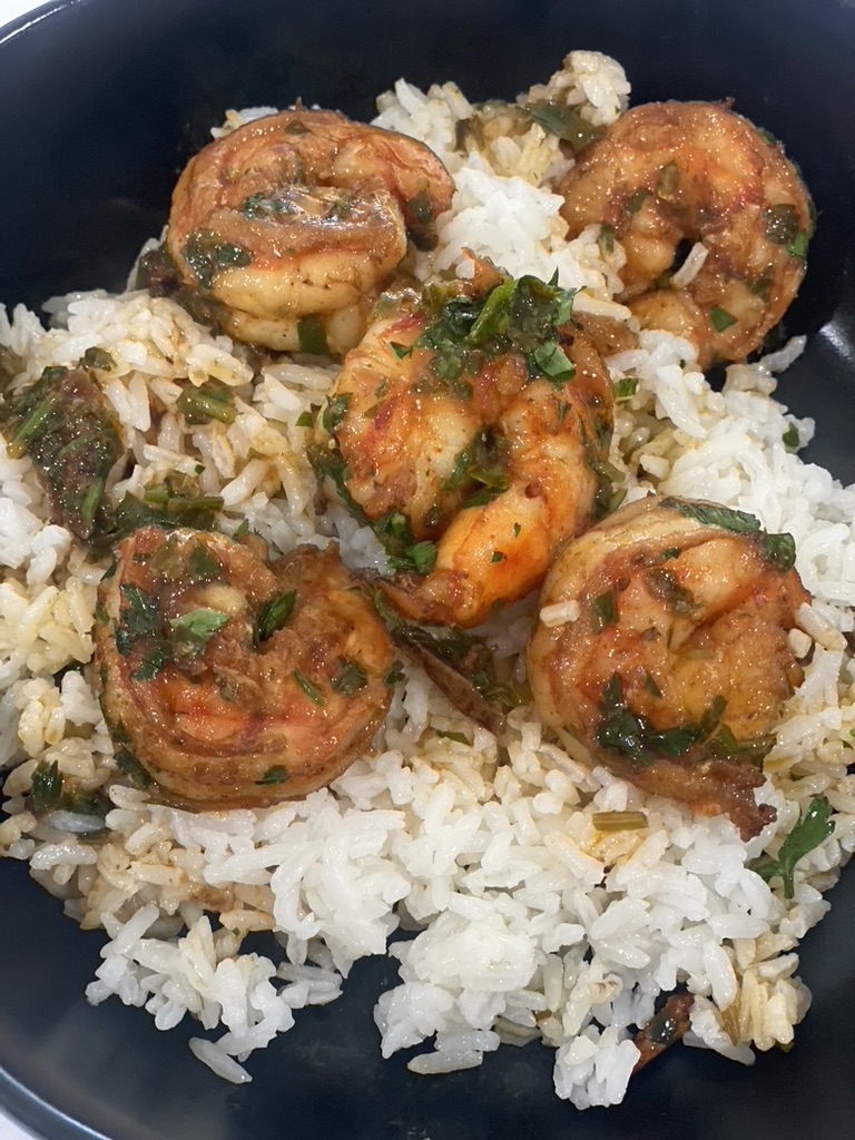 A plate of rice and shrimp with sauce.