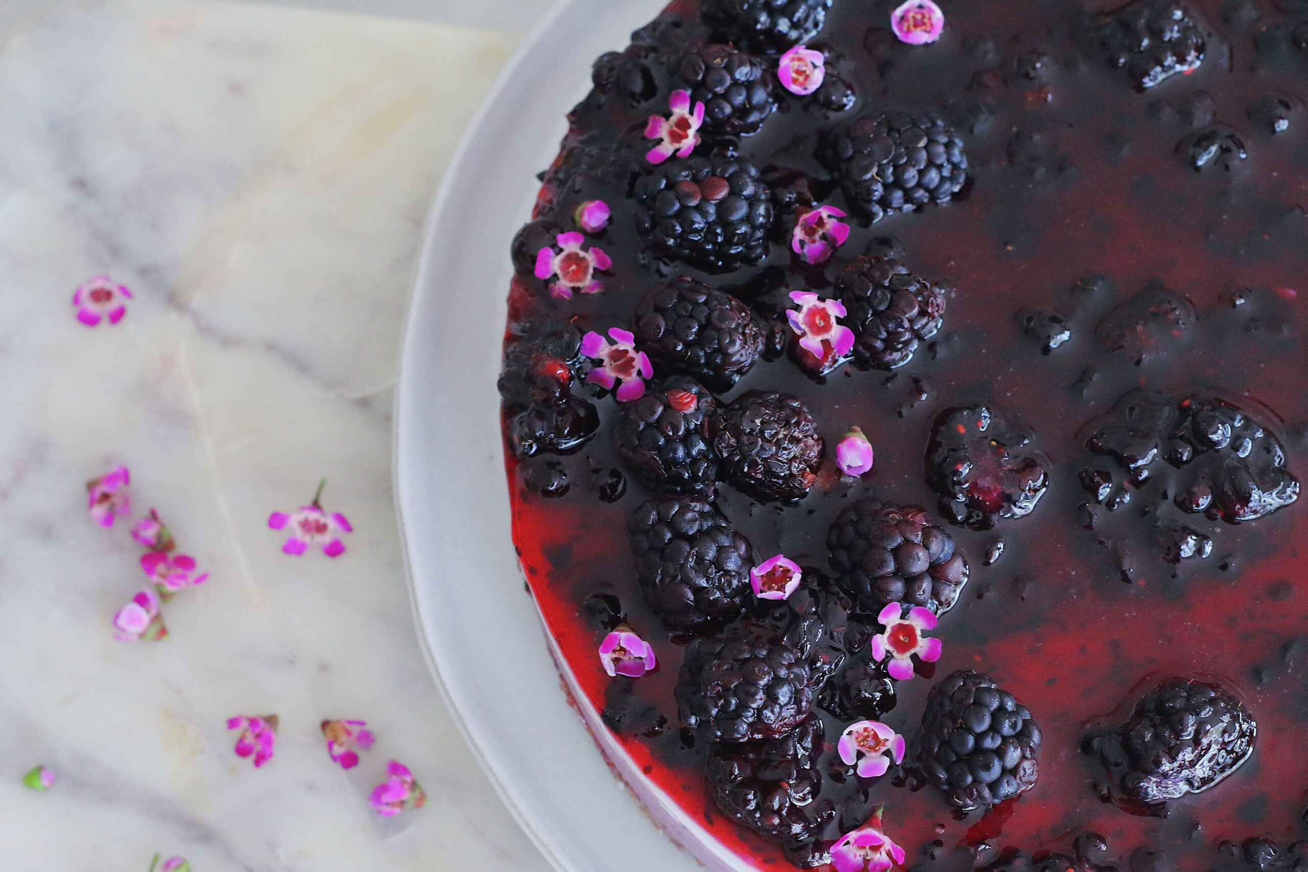 A white plate topped with a berry covered cake.