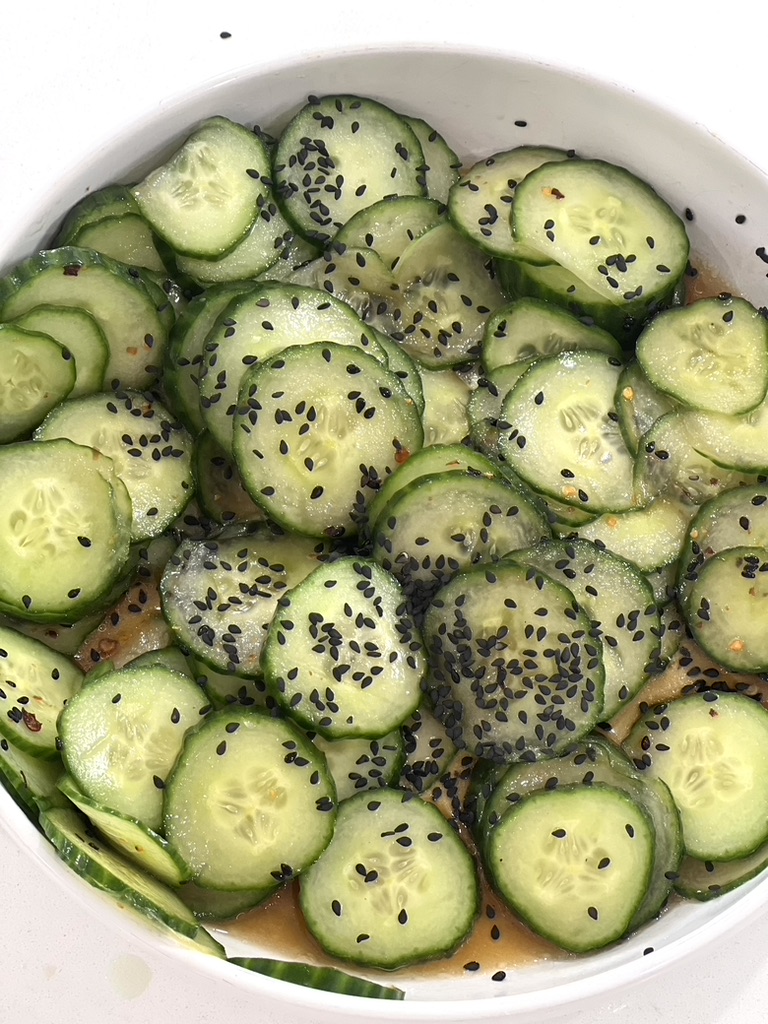A bowl of cucumbers with sesame seeds.