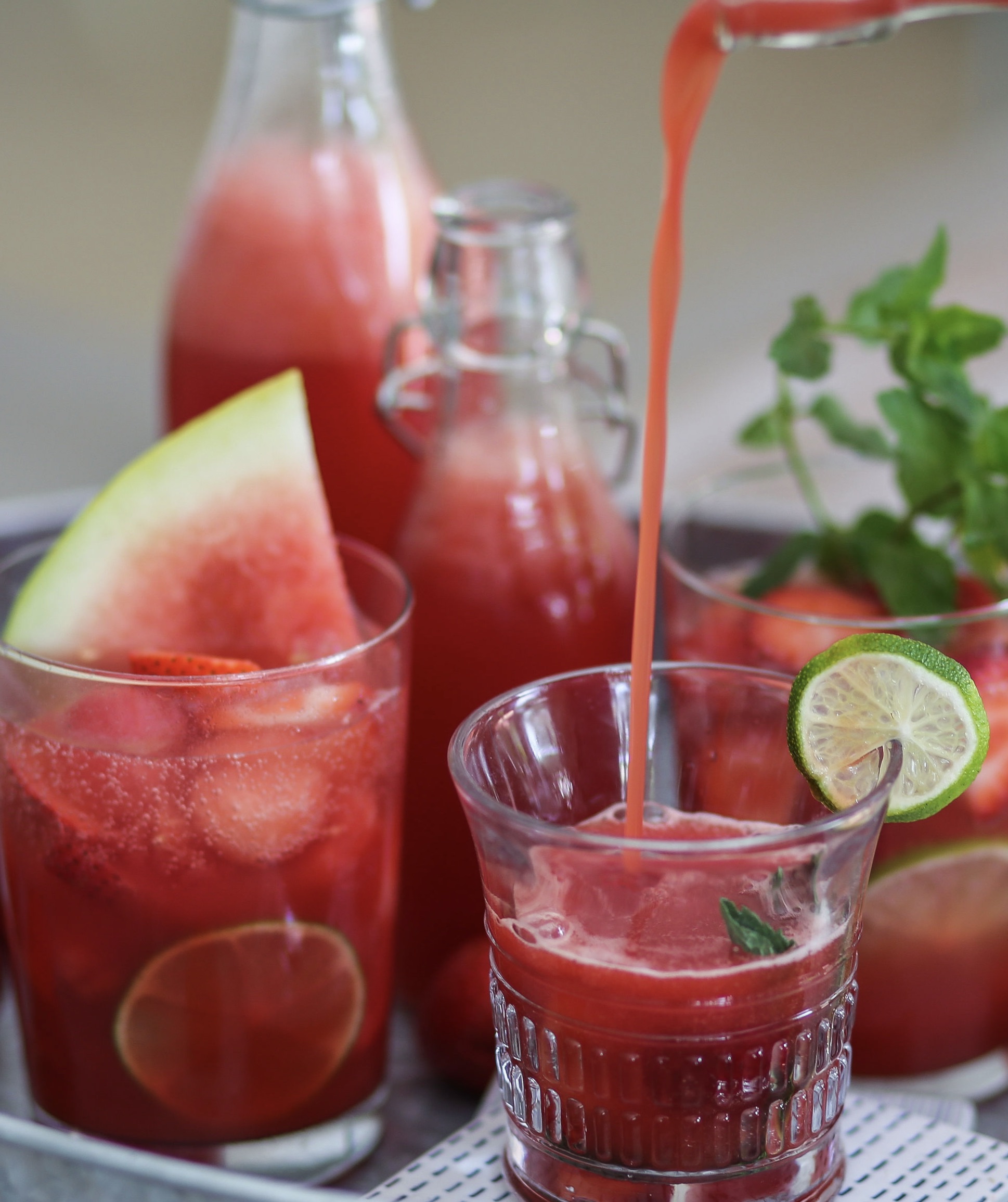 A table with glasses of watermelon juice and limes.