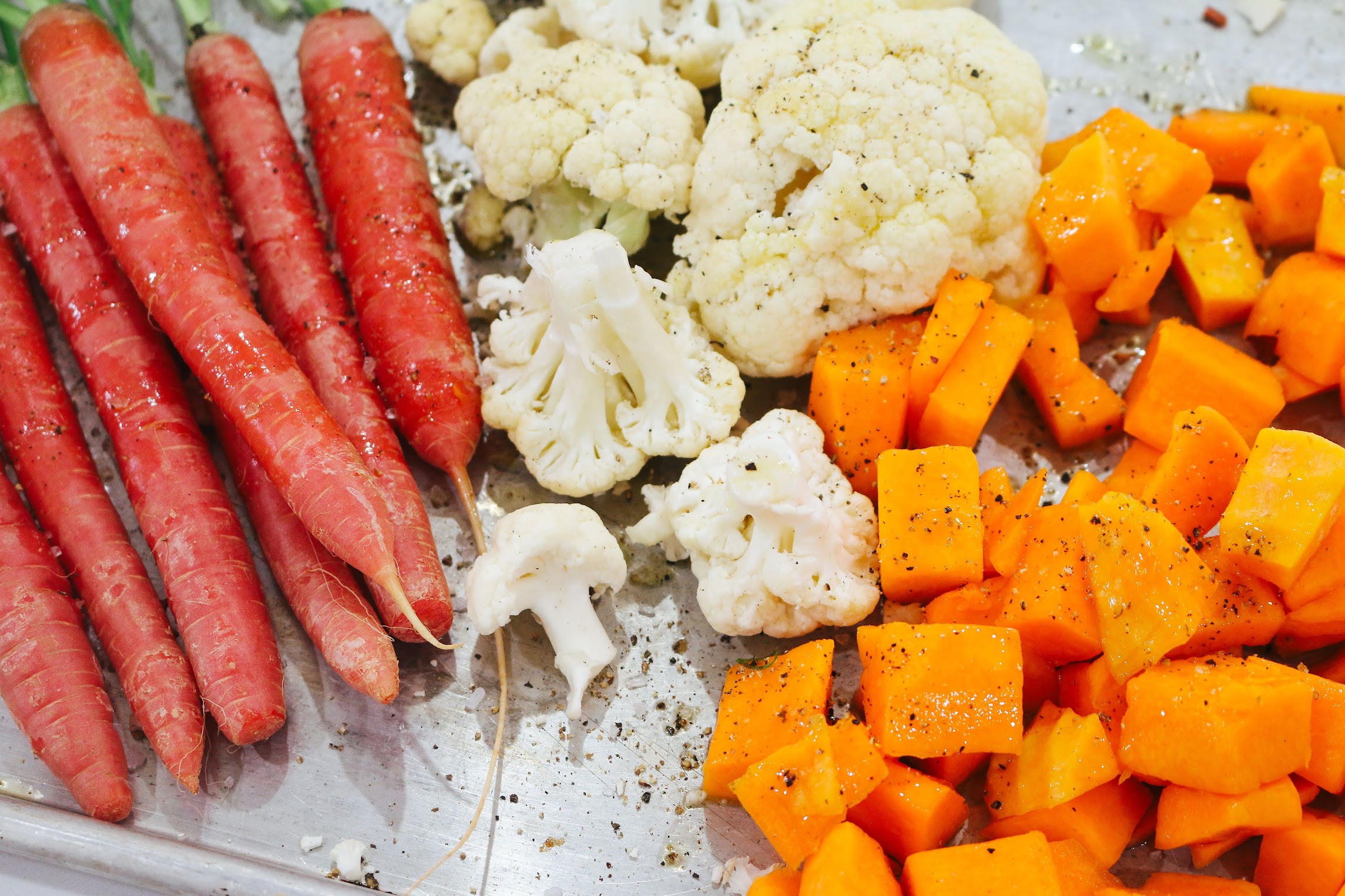 A plate of food with carrots, cauliflower and broccoli.