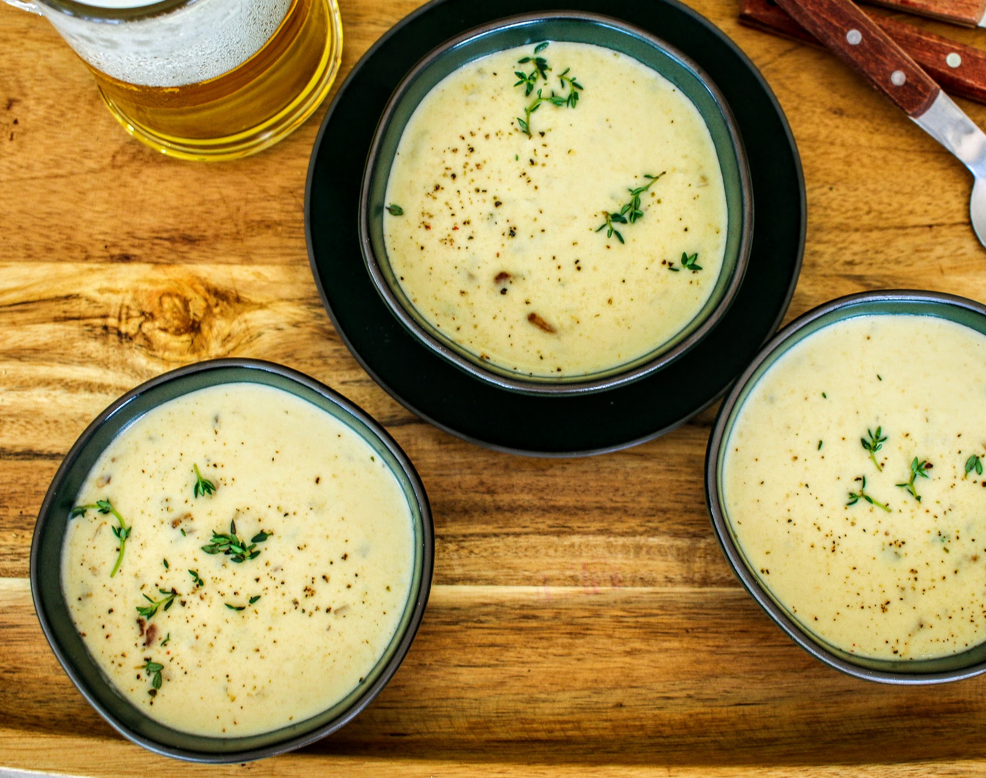 Three bowls of soup on a wooden table.