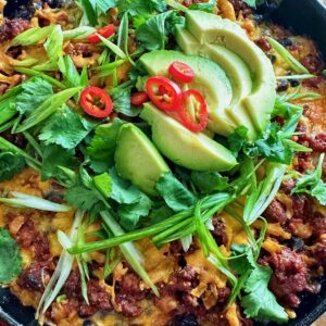 A bowl of food with avocado and chili.