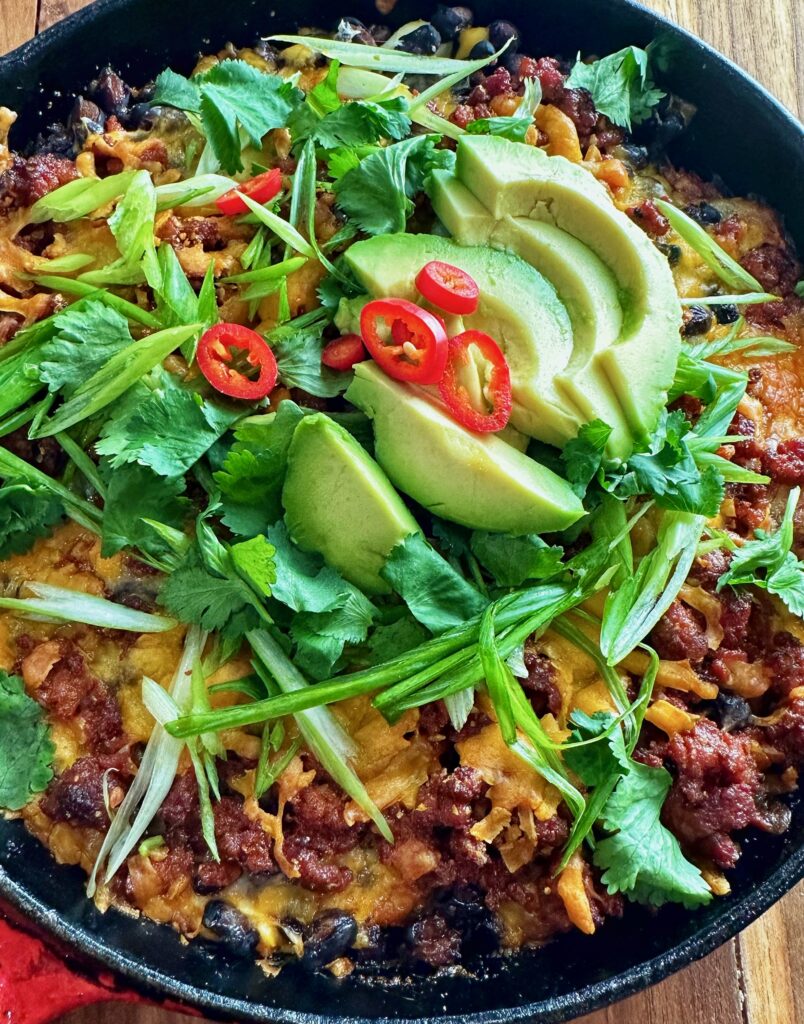 A bowl of food with avocado and chili.