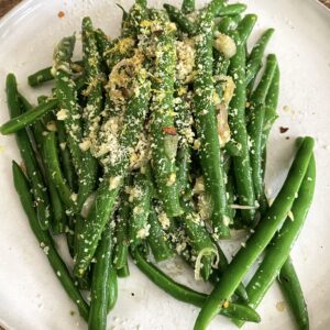 A plate of green beans with garlic and lemon.