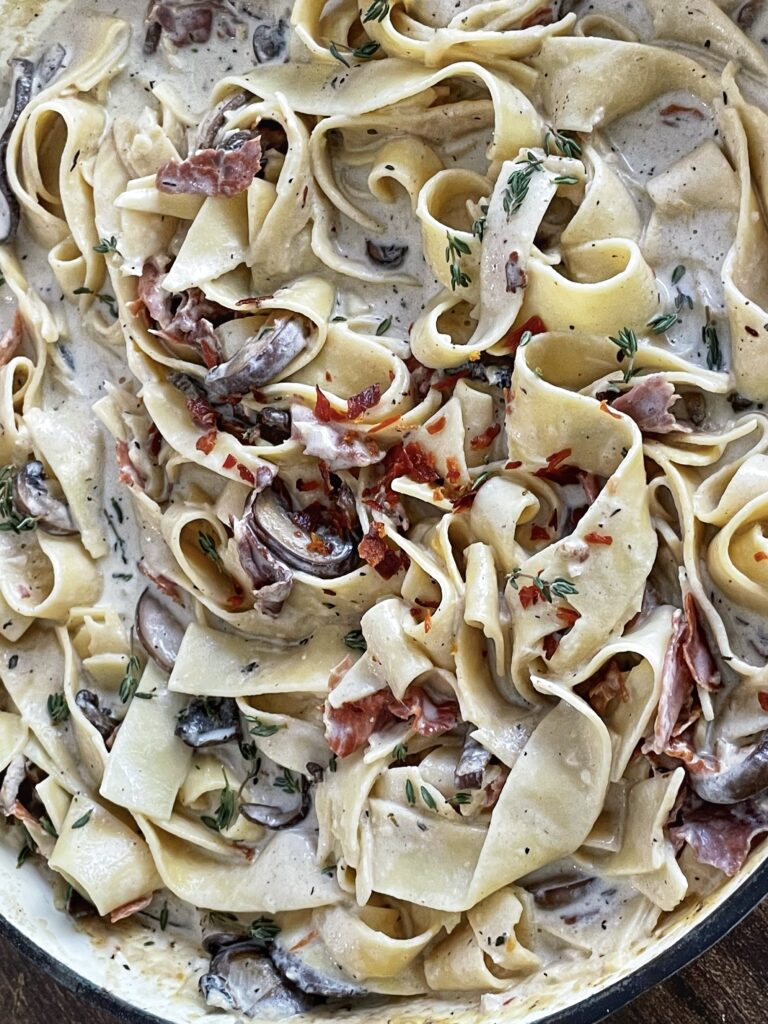 A close up of pasta with mushrooms and bacon