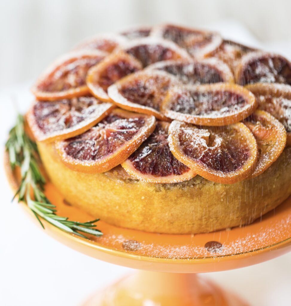 A cake with sliced oranges on top of it.