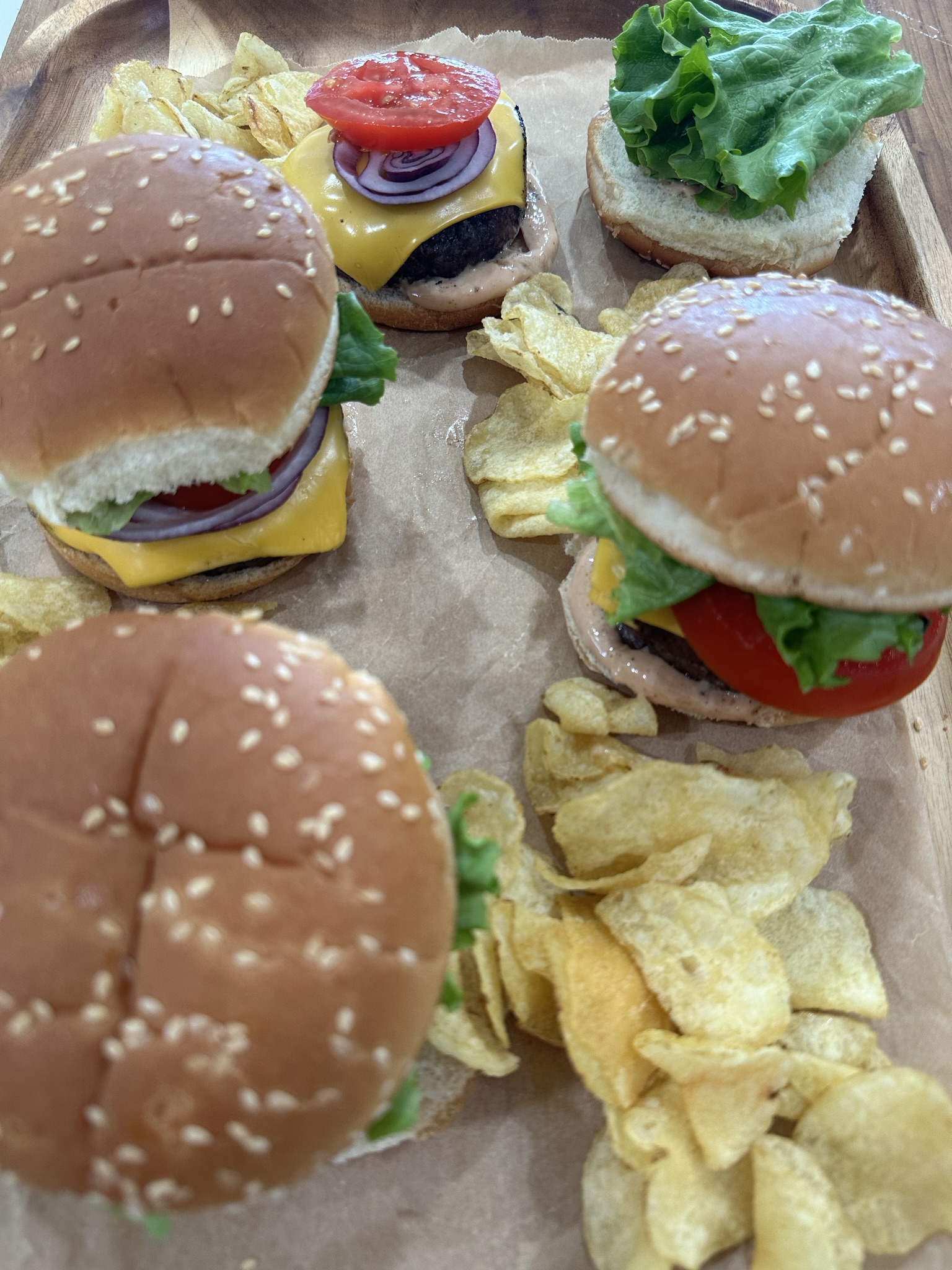 A tray of hamburgers and chips on the table.