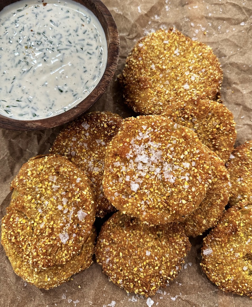 A pile of baked falafel next to a bowl of dip.