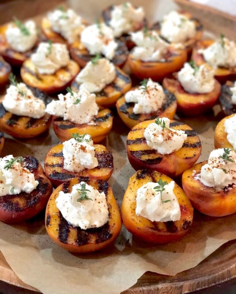 A platter of grilled peaches with whipped cream.