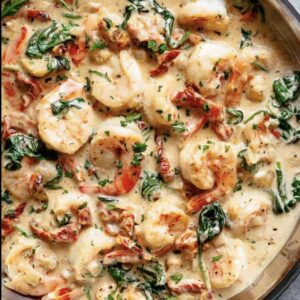 A pan of shrimp and spinach covered in sauce.