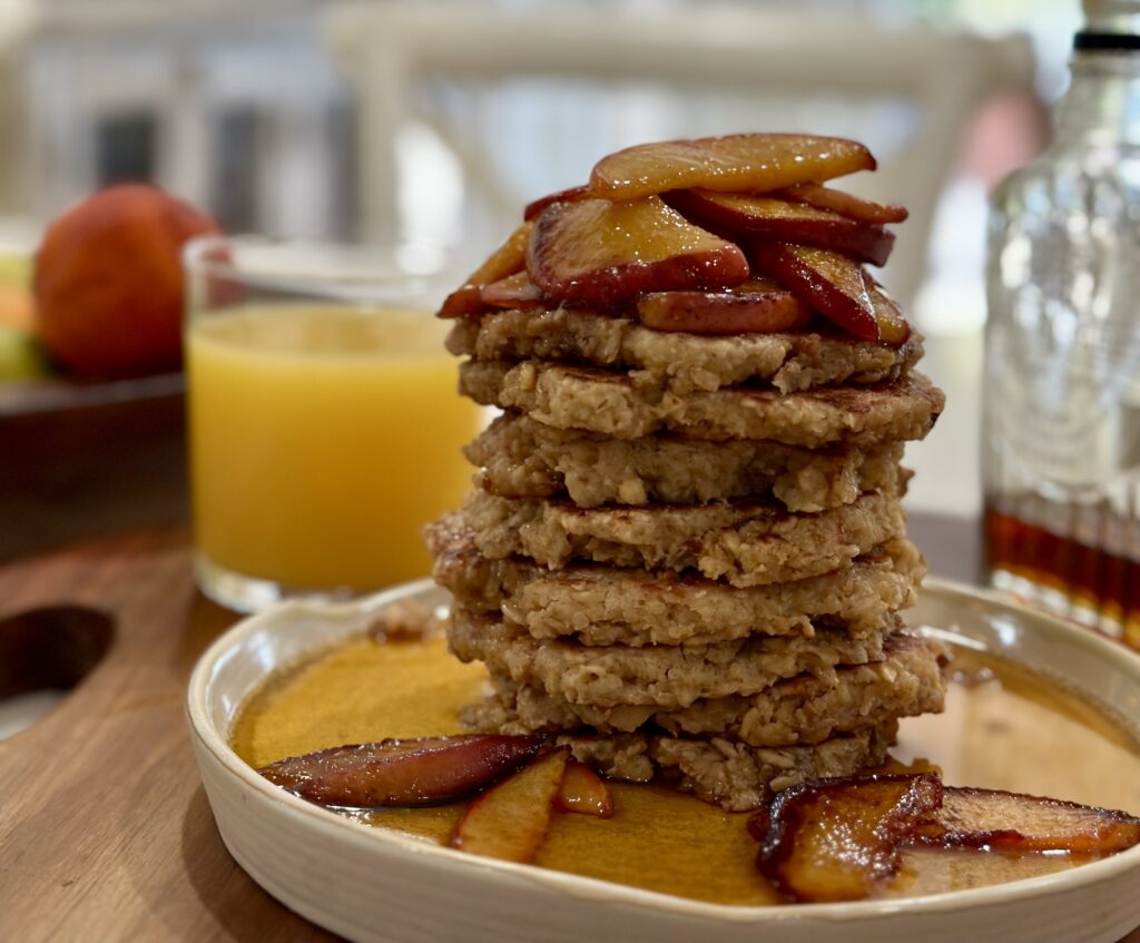 A stack of pancakes with bacon and peaches on top.