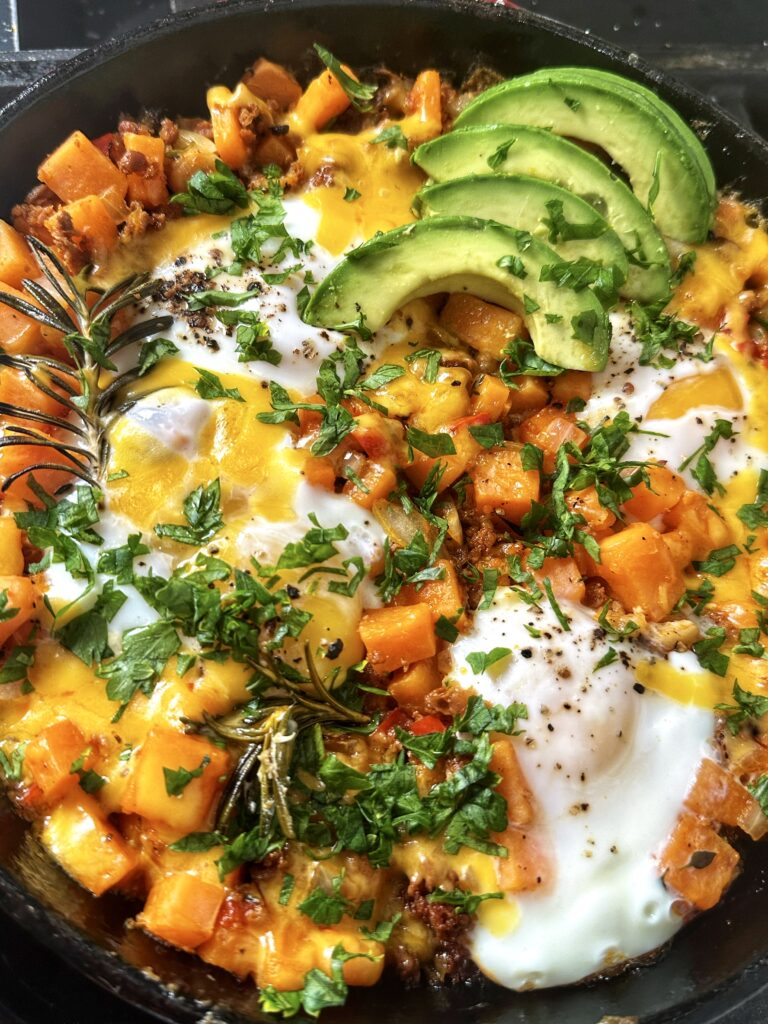 A bowl of food with potatoes, cheese and avocado.
