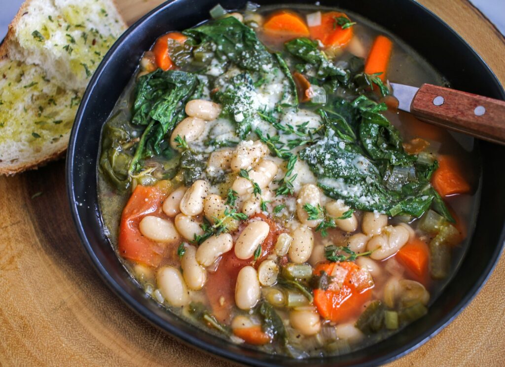 A bowl of beans and greens on the table.