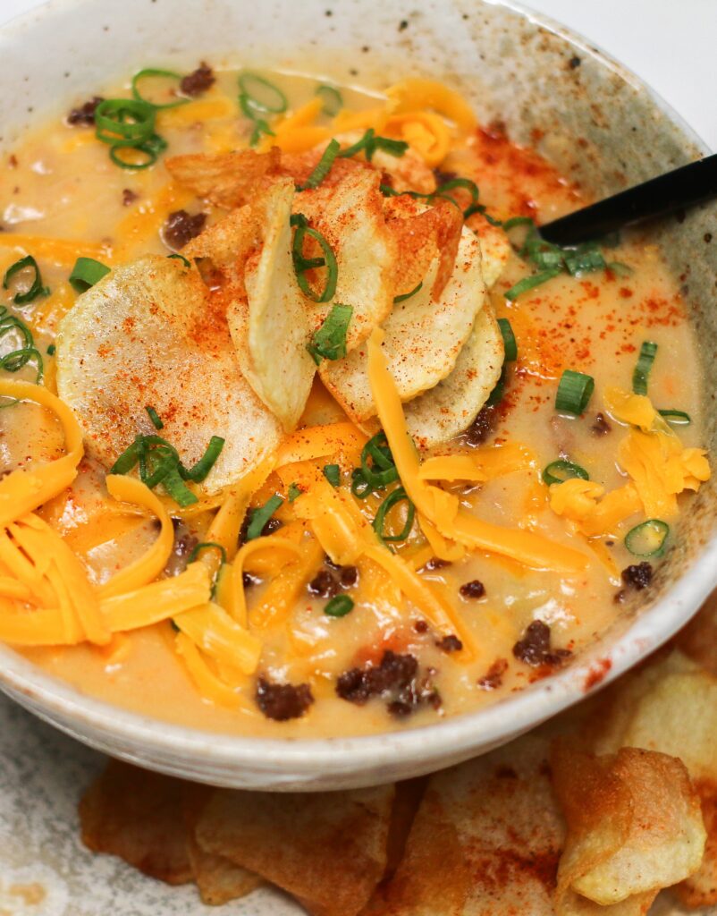 A bowl of soup with cheese and toppings.